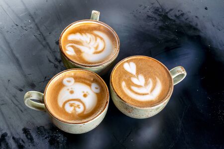 Three aroma cappuccino coffee cups with picturesの写真素材