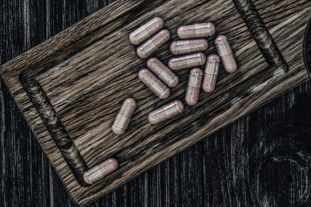 Pills on a cutting board on a dark wooden background. Toned.の写真素材