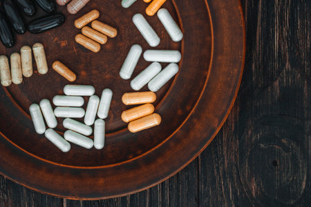 Colorful pills on a plate on a dark wooden background, top viewの写真素材