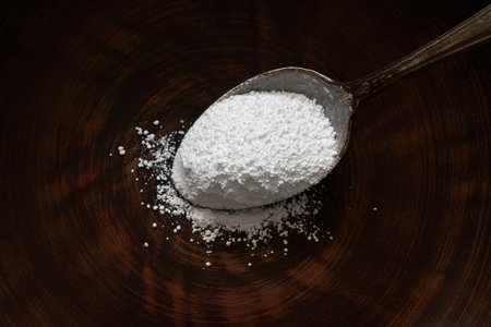 Close up of a spoon full of white powder on a wooden plate