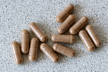 Pills in brown capsules on a gray background. Top view.