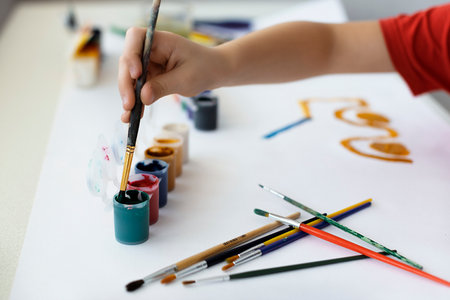 Little boy painting with watercolor paints on white sheet of paper.の写真素材