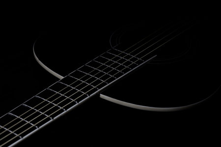 Acoustic guitar on a black background. Close-up. Selective focus.