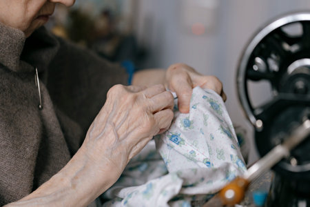 closeup of sewing on vintage sewing machine with senior female hands. selective focus photoの写真素材