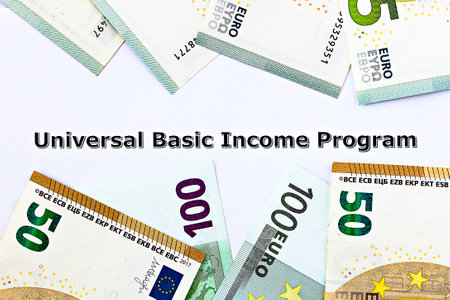 Topview photo on Universal Basic Income theme. The words Universal Basic Income program on paper, surrounded by euro banknotesの写真素材