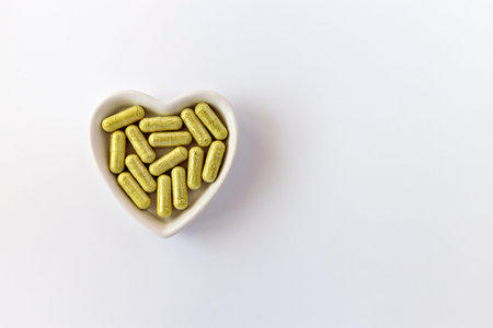 close-up of rutin capsules. dietary concept: a porcelain bowl in the form of a heart full of rutin...