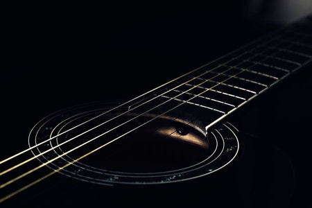 low-key photo of a fragment of a black guitar against a dark background. guitar music photo aestheticの写真素材