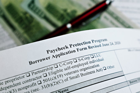 selective focus photo of paycheck protection program borrower application form revised, on a background of dollar bills and a penの写真素材