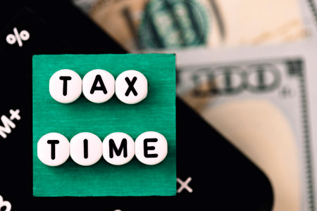 Photo on tax time theme. The inscription "Tax time" on a green square, on the background of calculator and dollar billsの写真素材