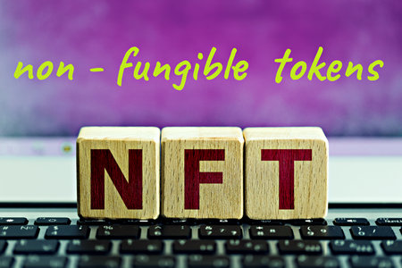 photo on nft (non-fungible token) theme. wooden cubes with the abbreviation "nft", and the inscription "non-fungible tokens", on lilac backgroundの写真素材