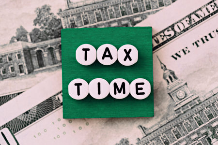 Photo on tax time theme. The inscription "Tax time" on a green square, on the background of dollar billsの写真素材