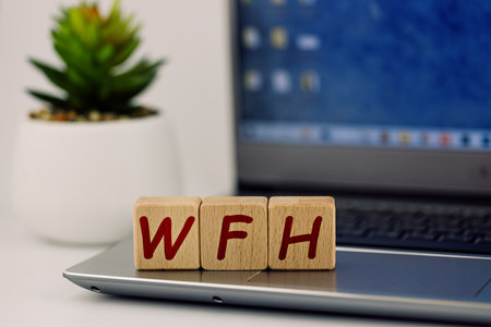 photo on WFH (work from home) theme. wooden cubes with the acronym "WFH", on the background of laptop and succulentの写真素材
