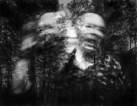 A black and white image of a man screaming in a forest with a blurred background