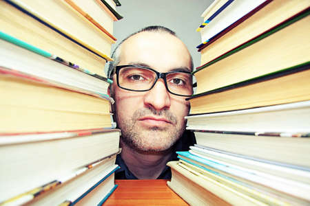 portrait of a man wearing glasses a lot of booksの写真素材