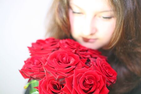 the girl looks at a bouquet of red rosesの写真素材