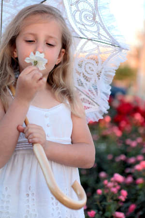 girl with umbrella sniffing a flowerの写真素材