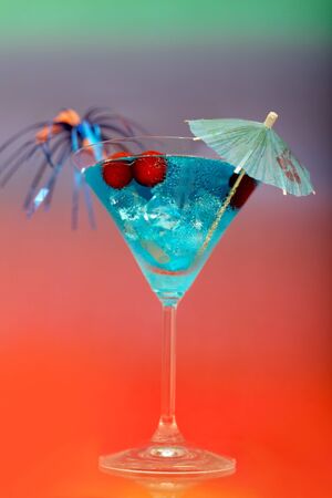 blue cocktail with ice and umbrella on a colored backgroundの写真素材