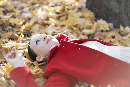 pretty girl lying in autumn leaves dayの写真素材