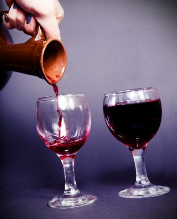 pouring wine from an ancient pitcher dark backgroundの写真素材