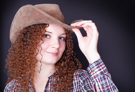 portrait of a pretty curly girl the cowboy on a dark backgroundの写真素材