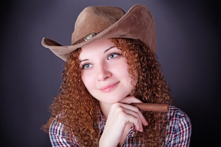 pretty curly red-haired girl with a cigar dark backgroundの写真素材