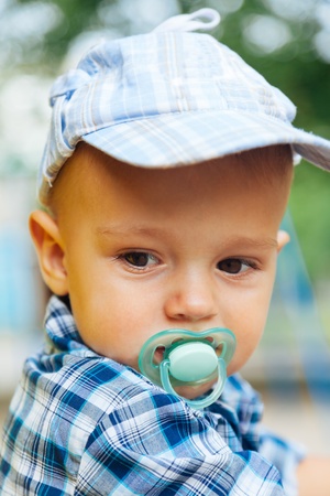 portrait of baby with pacifier outside in the summerの写真素材