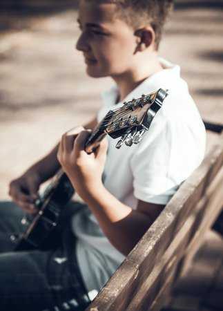 boy learning to play guitar in the park