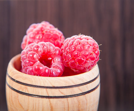 fresh raspberries in wooden bowl closeup