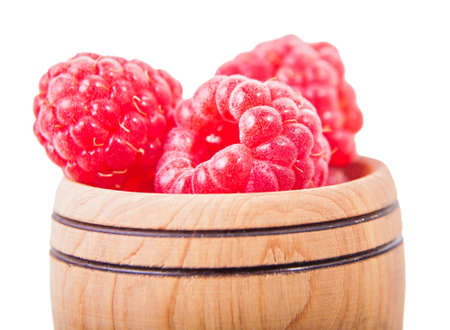 raspberries in wooden bowl closeup isolated white backgroundの写真素材
