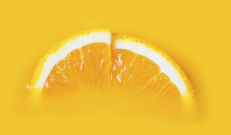 Two fresh a slice of orange on yellow backgroundの写真素材