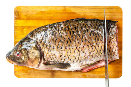 cleaned fish lying on a wooden board with knifeの写真素材