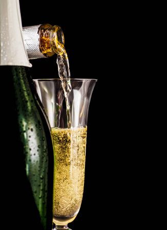 Champagne is poured into glass on a dark backgroundの写真素材