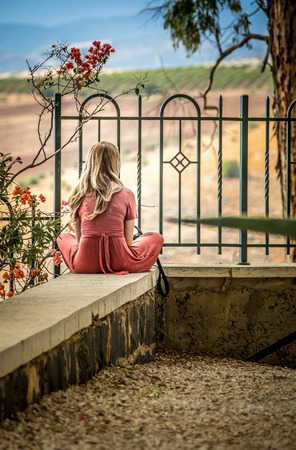 blonde girl in a pink dress sitting backの写真素材