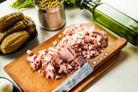 on a wooden board sliced sausage and ingredients for a saladの写真素材