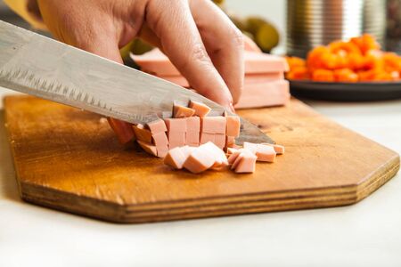 cook woman cuts a knife sausage cubes closeupの写真素材