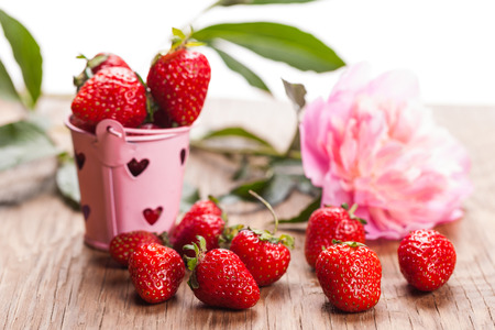 bucket of strawberries and peony on a wooden backgroundの写真素材