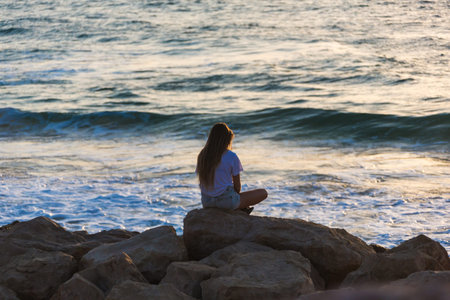 young woman sitting on the rocky seashore