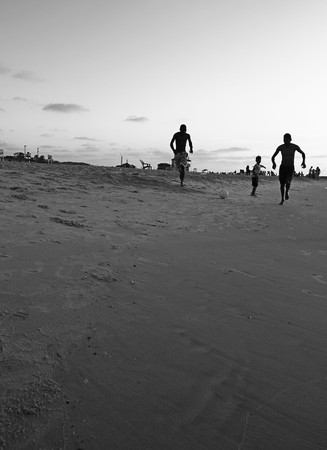 boys running along the sandy sea shoreのeditorial素材