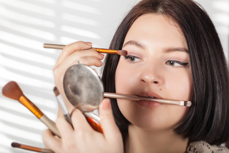 the girl does make-up on a white backgroundの写真素材