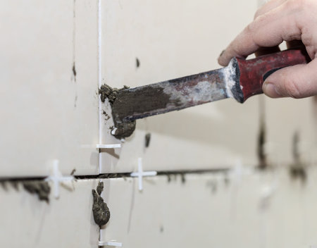 Worker tiler puts ceramic tiles on a wall