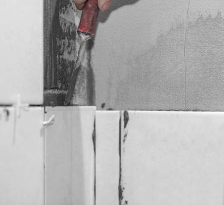 Worker tiler puts ceramic tiles on a wallの写真素材