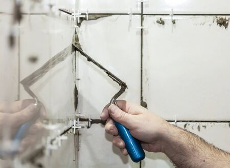 Worker tiler puts ceramic tiles on a wallの写真素材