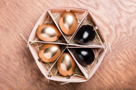 gold and black chicken eggs on wooden backgroundの写真素材