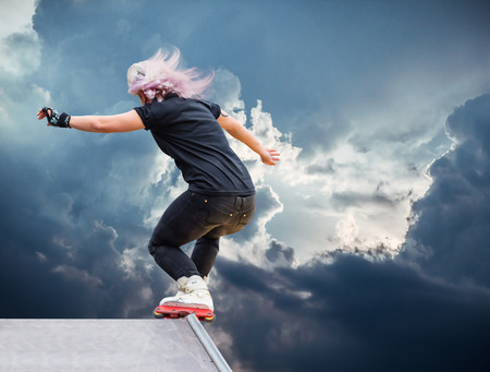 girl roller performs a trick against the skyの写真素材