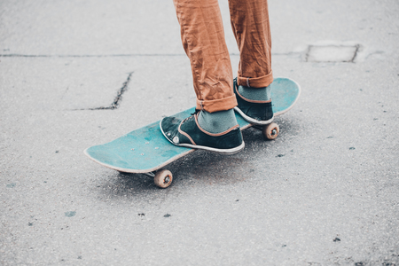 Young skateboarder in gumshoes standing on skateの写真素材