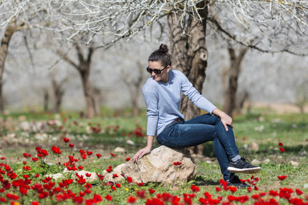 woman relaxing in a field with red poppiesの写真素材