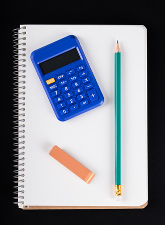 notebook, calculator, eraser and pencil on a black backgroundの写真素材