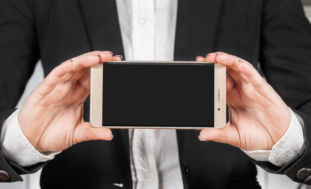 woman in business suit holds a smartphone closeupの写真素材