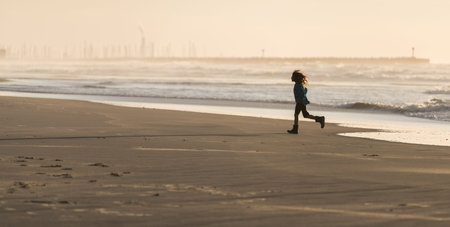 child girl runs along the sea shoreの写真素材