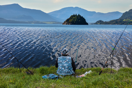 Man with fishing rods fishing in the lakeの写真素材